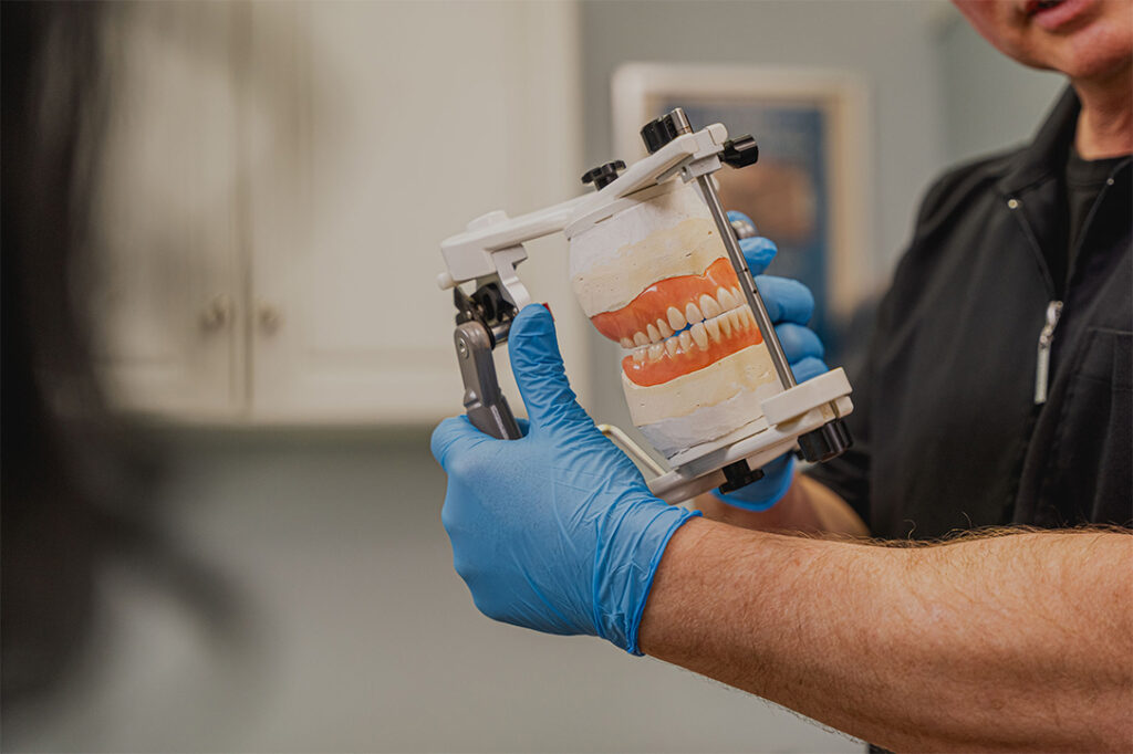 Michael Battell holding a full set of upper and lower complete dentures