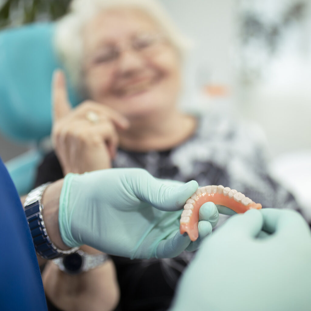 Stock photo of woman being fitted for complete denture, the woman is blurred out but smiling