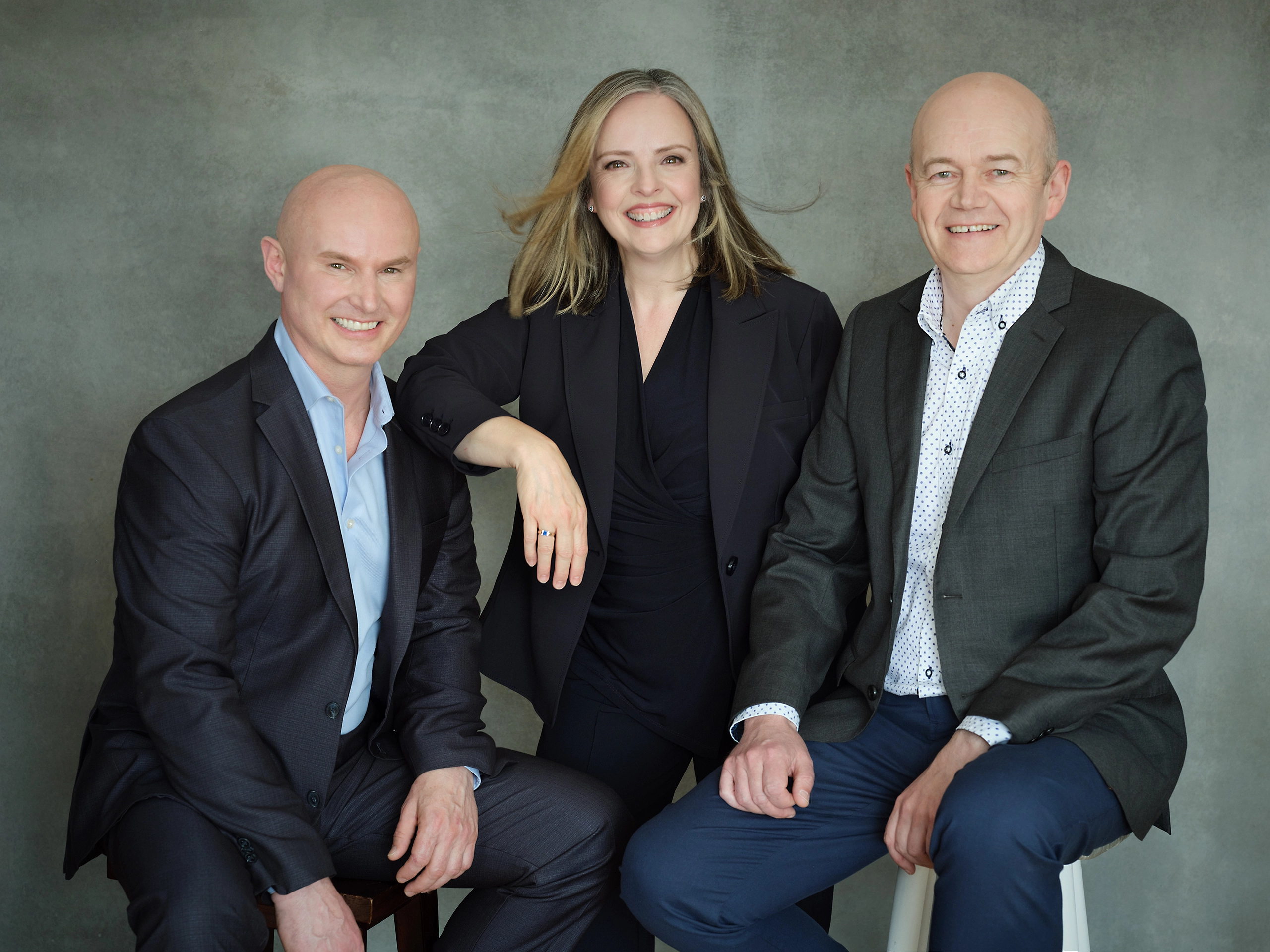 Michaell Battell, Trish and Pavlo standing side by side smiling in business casual attire.